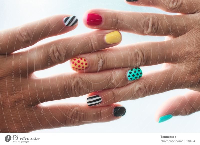 Ein Paar weibliche Hände mit farbig bemalten Nägeln. Fingernagel polnisch gemalt Farben und Lacke Muster mehrfarbig Design außergewöhnlich Behandlung Kunst Gel