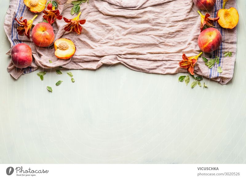 Lebensmittelhintergrund mit frischen ganzen und halben Pfirsichen auf Küchentuch mit Blättern, Blumen und Kopierfläche für Ihr Design oder Produkt, Draufsicht. Flacher Schlag. Horizontal. Grenze