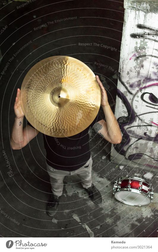 Schlagzeuger mit Becken auf dem Kopf im dunklen urbanen Umfeld. Lifestyle Freude sportlich Wellness Leben Freizeit & Hobby Spielen Handarbeit Freiheit