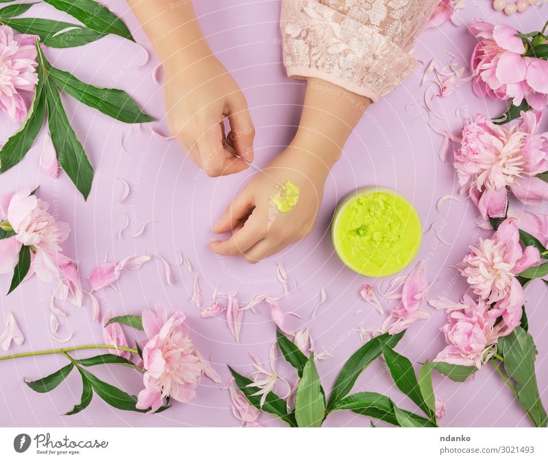 weibliche Hände und ein Glas mit dickem grünem Peeling Körper Haut Behandlung Wellness Spa Sommer Frau Erwachsene Hand Finger Pflanze Blume Blatt Mode