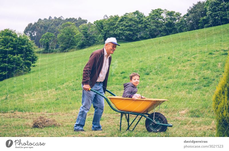 Glücklicher älterer Mann gibt niedlichen Jungen Fahrt auf Schubkarre Lifestyle Freude Freizeit & Hobby Spielen Sommer Garten Kind Gartenarbeit Mensch Erwachsene