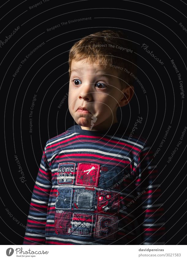 Verwirrter Junge mit Zweifelsgesicht über schwarzem Hintergrund Gesicht Kind Mensch Mann Erwachsene Kindheit Hemd Streifen Denken stehen authentisch dunkel