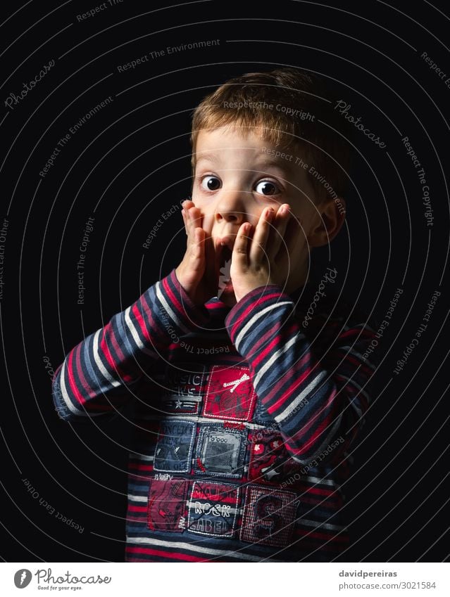 Überraschender Junge schaut in die Kamera auf schwarzem Hintergrund Freude Glück Gesicht Kind Mensch Mann Erwachsene Kindheit Mund Arme Hand Streifen stehen