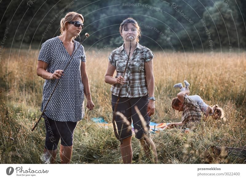 Frauen, die einen Marshmallow über einem Lagerfeuer braten. Lifestyle Freude Glück Erholung Freizeit & Hobby Spielen Ferien & Urlaub & Reisen Sommer