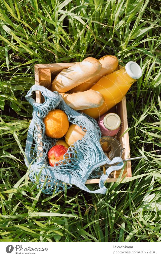 Verschiedene Früchte und kalte Getränke in einer Holzkiste Picknick Ökobeutel Baguette Brot Diät Glas Flasche Milchshake Saft orange Apfel Frucht