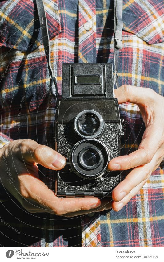 Nahaufnahme der Hände des Mannes, der eine Vintage-Kamera hält. retro einfangen Außenaufnahme Fotografie schießen alt kariertes Hemd gesichtslos Linse