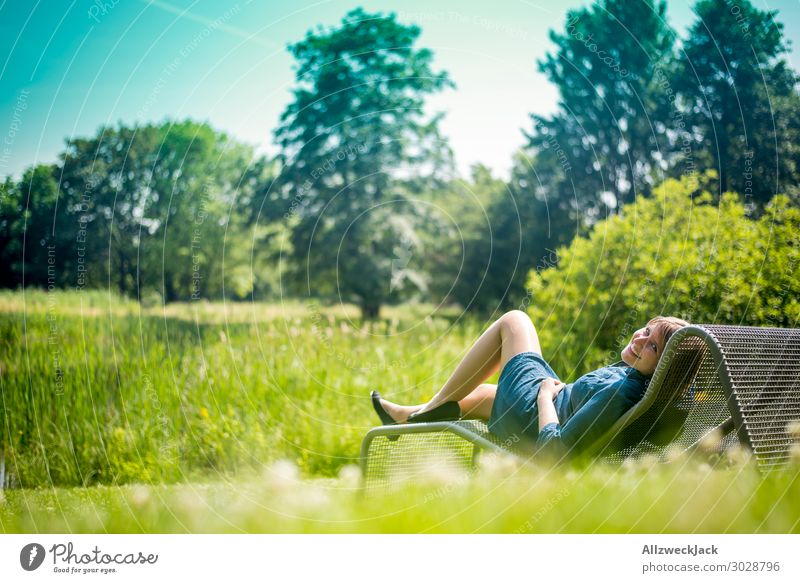 junge Frau sonnt isch auf einer Liege im Garten Schönes Wetter Wolkenloser Himmel Blauer Himmel grün Natur Wiese Rasen Sonnenbad genießen Erholung Pause