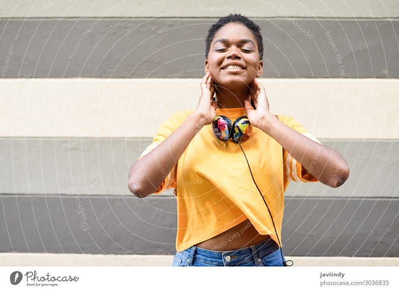 Glückliche afrikanische Frau lächelt an der Stadtmauer mit geschlossenen Augen. Lifestyle Stil schön Haare & Frisuren Gesicht Musik Headset Mensch feminin