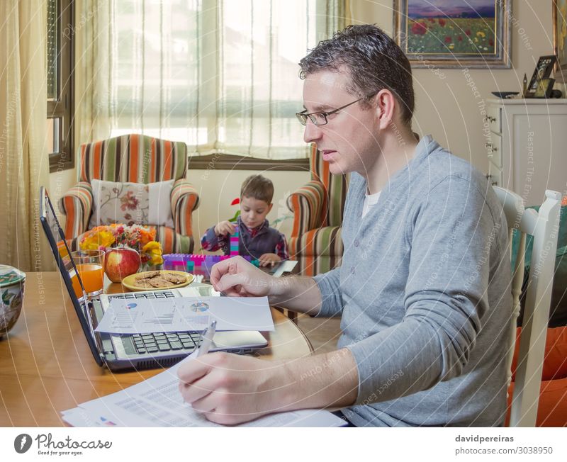 Vater arbeitet im Home Office mit Notebook und sein Sohn spielt im Hintergrund Lifestyle Leben Haus Sofa Kind Arbeit & Erwerbstätigkeit Büro Business Telefon