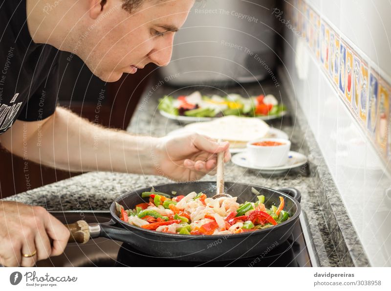 Mann kocht Gemüse und Huhn in einer Pfanne. Erwachsene frisch heiß grün rot Tradition Hähnchen Peperoni Koch Mais fajita Lebensmittel Salat Mexikaner Mexiko