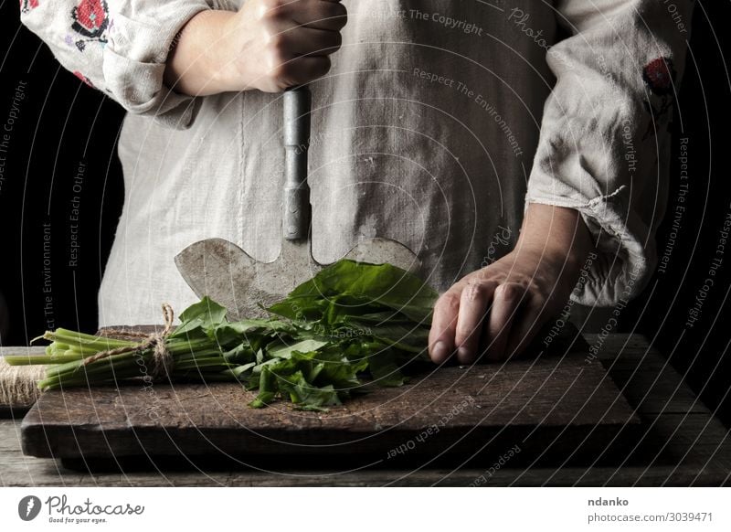Frau schneidet grüne Blätter von frischem Sauerampfer. Gemüse Suppe Eintopf Kräuter & Gewürze Ernährung Vegetarische Ernährung Messer Tisch Küche Erwachsene