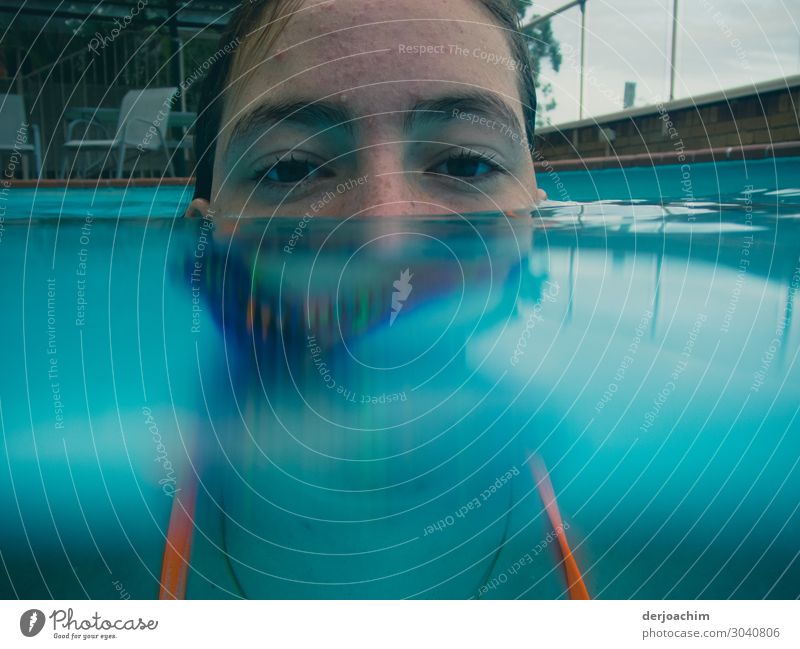 Halb unter Wasser ist das Gesicht eines Mädchens im Pool. Man sieht nur die Augen und die Stirn. Freude Erholung Sommer feminin Junge Frau Jugendliche