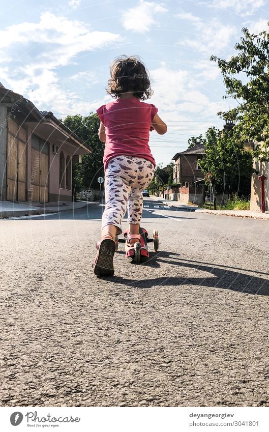 Kleines Mädchen spielt mit dem Roller auf der Straße. Freude Leben Freizeit & Hobby Spielen Sonne Sport Bewegung niedlich Tretroller Kind Frühling Großstadt