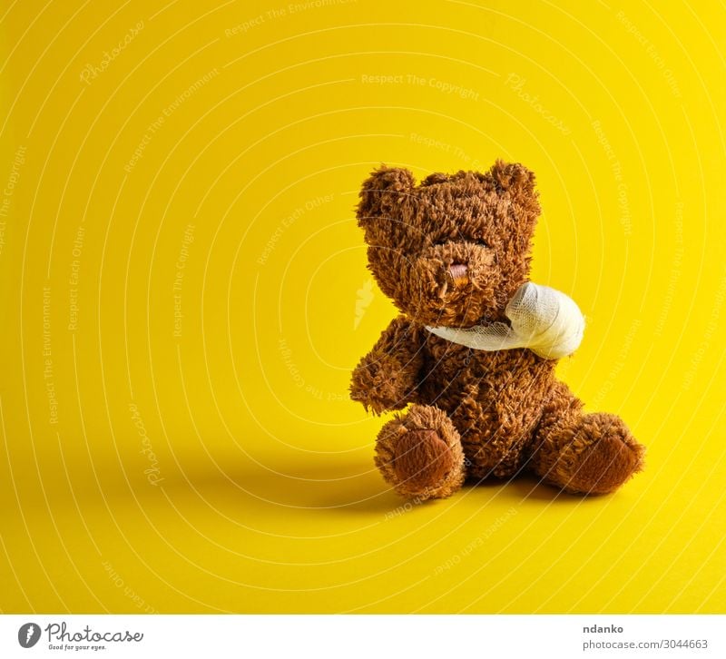 brauner Teddybär mit einer bandagierten Pfote sitzend Freude Behandlung Krankheit Medikament Kind Krankenhaus Kindheit Spielzeug Puppe klein lustig niedlich
