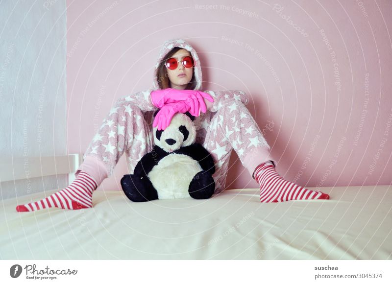 jugendliche mit pinkfarbenen gummihandschuhen sitzt auf ihrem bett mit ihrem kuscheltier und rosa sonnenbrille auf Teenager Jugendliche Junge Frau Kindheit doof