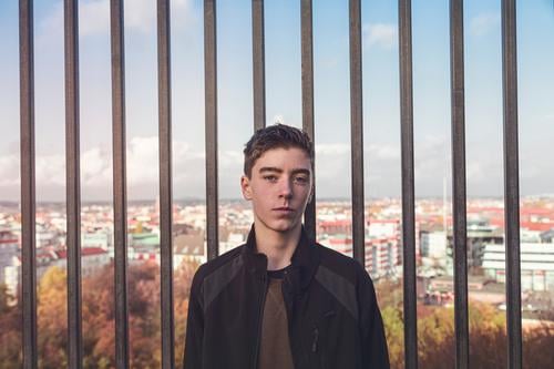 Porträt eines lächelnden jungen Mannes vor Bars und Berlin Architektur Herbst schön Borte Junge lässig Kaukasier selbstbewusst Europa Spaß Deutschland Raster