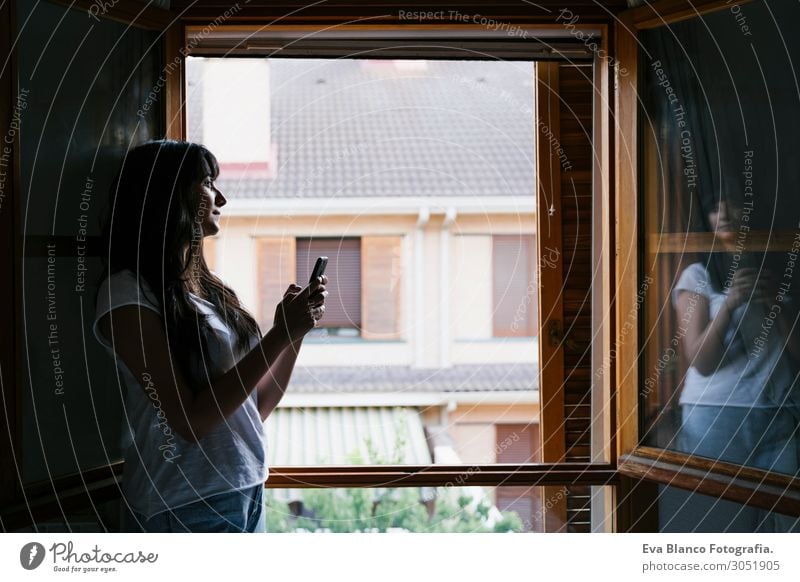 junge kaukasische Frau am Fenster mit dem Handy Lifestyle Glück Erholung Freizeit & Hobby Spielen lesen Ferien & Urlaub & Reisen Haus Schlafzimmer Telefon PDA