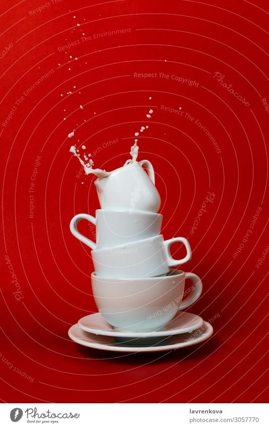 Tassen und Untertassen mit Milchkännchen oben und Spritzwasser innen Getränk Frühstück Kaffee Geschirr Tropfen Flüssigkeit liquide Morgen Bewegung Becher rot