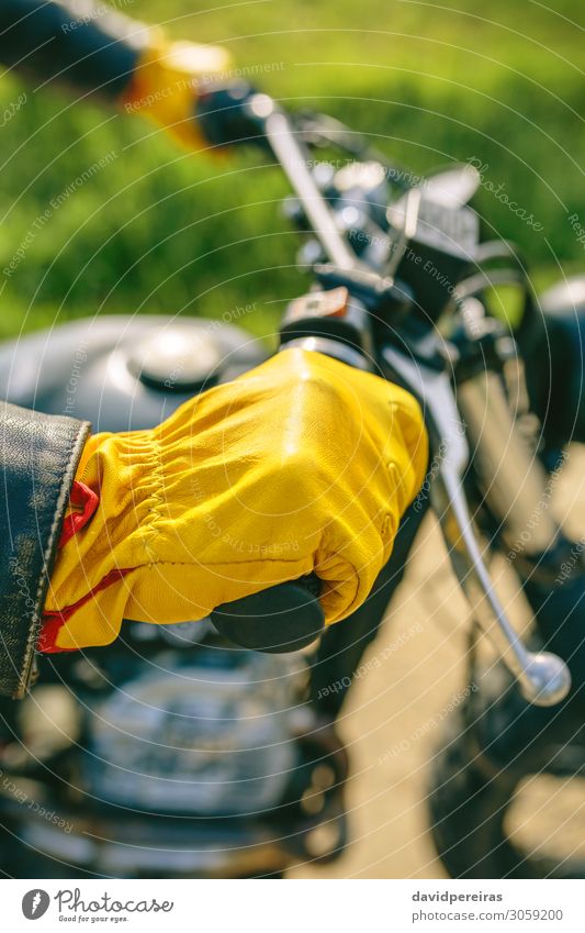 Bikerhand mit Handschuhen, die den Lenker greifen. Lifestyle Motor Mensch Mann Erwachsene Gras Verkehr Straße Fahrzeug Motorrad authentisch retro gelb