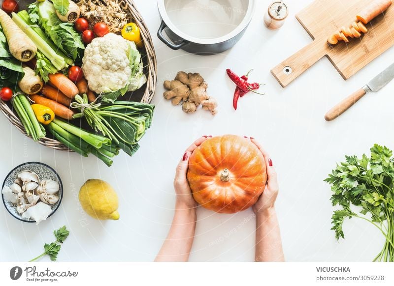Frauenhände halten Kürbis auf weißem Küchentisch Lebensmittel Gemüse Ernährung Bioprodukte Vegetarische Ernährung Diät Geschirr Topf Lifestyle kaufen Stil