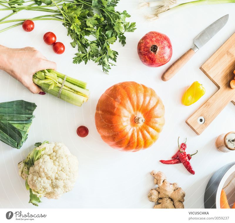 Küchentisch mit Gemüse und Hand mit Stangensellerie Lebensmittel Ernährung Bioprodukte Vegetarische Ernährung Diät Geschirr Lifestyle Design Gesunde Ernährung