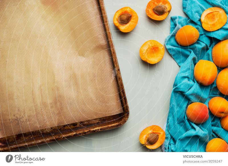 Lebensmittelhintergrund mit frischem ganzen und halbierten Aprikosenstrauß und leerem Backblech, Ansicht von oben. Konzept für saisonale Früchte. Haufen