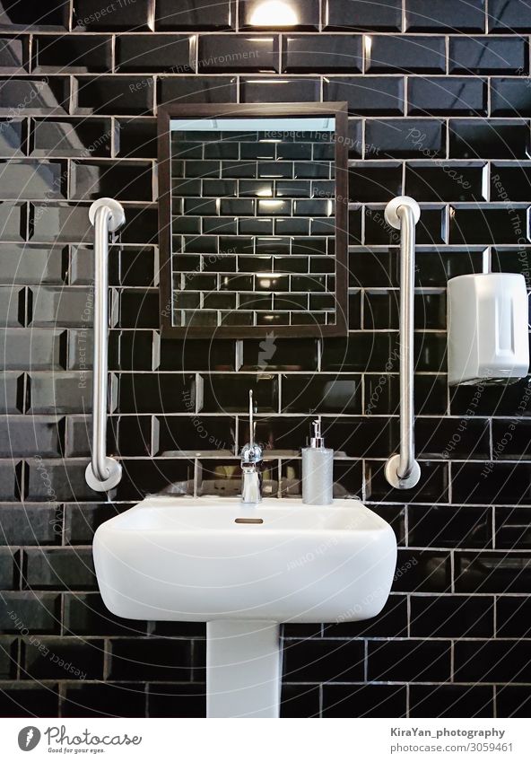 Modernes Design des Toilettenraumes mit schwarzen, glänzenden Fliesen. Schwarze Glanzfliese für zeitgenössisches Dekorationsdesign. Abstrakter Fliesenhintergrund für die Heimdekoration