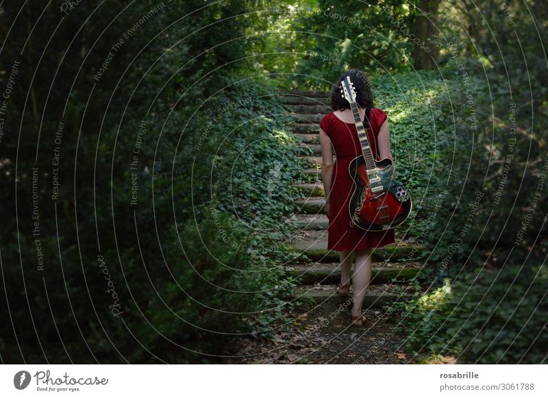 on the road again - musikalischer Aufstieg - brünette junge Frau geht mit roter Gitarre auf dem Rücken durch den Wald | allein mit Gitarre im Wald
