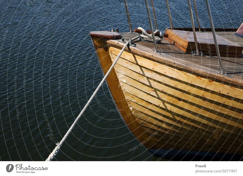 Holzboot in der Abendsonne Wasser Meer Wellen Schifffahrt Wasserfahrzeug Boot Leine Seil Festmacherleine festgemacht maritim Hafen Licht abends Schatten