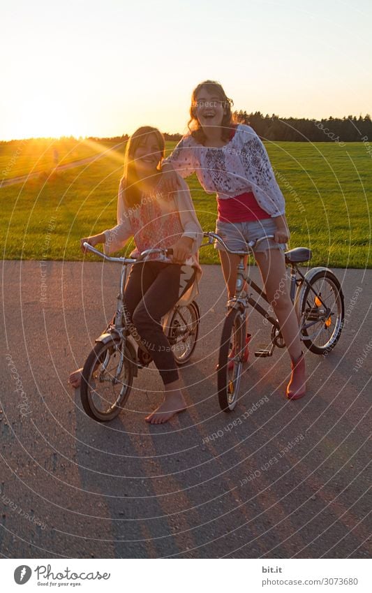 Zwei Mädchen auf Fahrrad, in der Natur bei Sonnenuntergang. Ferien & Urlaub & Reisen Ausflug Abenteuer Ferne Freiheit Freude Glück Fröhlichkeit Zufriedenheit