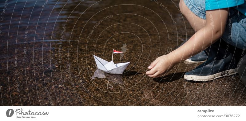 Kleiner Junge setzt kleines Papierschiff ins Wasser Freude Glück Gesundheit Alternativmedizin Erholung ruhig Schwimmen & Baden Spielen Basteln Modellbau