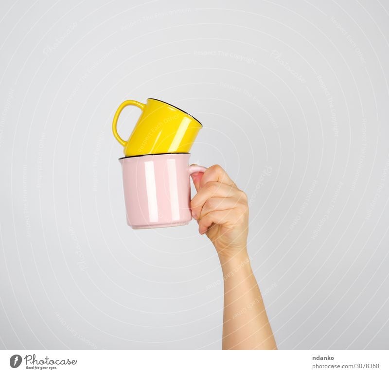 weibliche Hand, die einen Stapel Keramikbecher hält. Frühstück Kaffeetrinken Getränk Espresso Tee Design Küche Frau Erwachsene Arme Finger heiß gelb rosa weiß