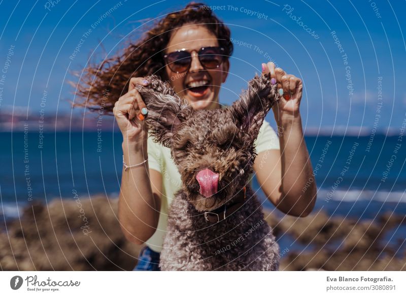 junge Frau und ihr süßer spanischer Wasserhund im Freien, die gemeinsam an einem sonnigen und windigen Tag genießen. Sommerzeit, Tierliebe und Ferienkonzept