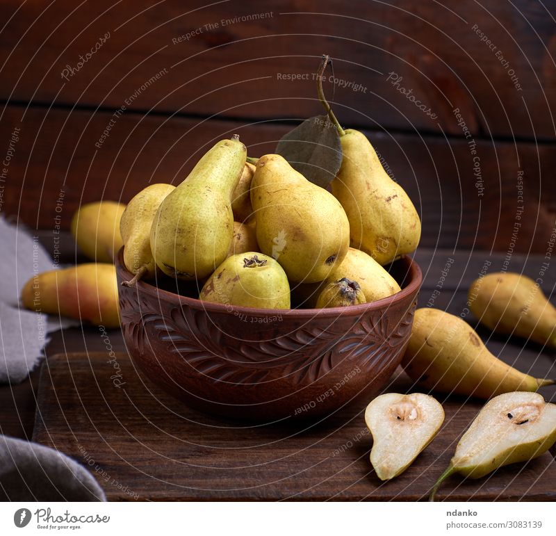 frische reife grüne Birnen in einer braunen Tonschale auf einem Tisch Frucht Ernährung Vegetarische Ernährung Diät Teller Schalen & Schüsseln Natur Herbst Holz