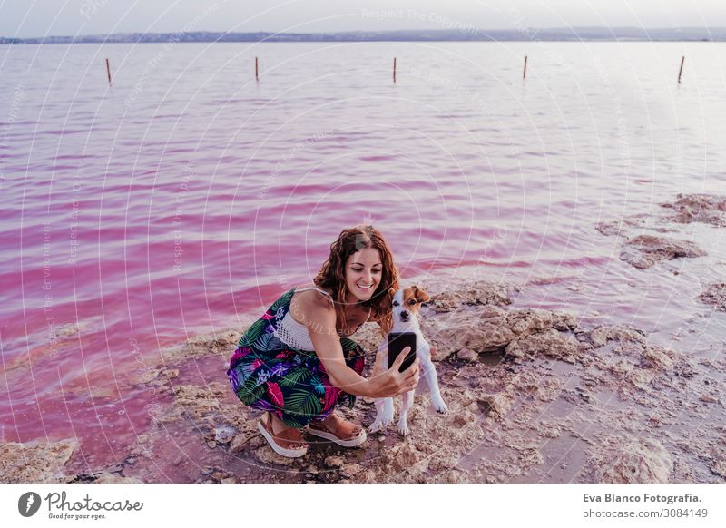 junge schöne Frau, die an einem rosa See mit Hund steht. Lifestyle Freude Glück Erholung Freizeit & Hobby Ferien & Urlaub & Reisen Tourismus Sommer Strand Meer