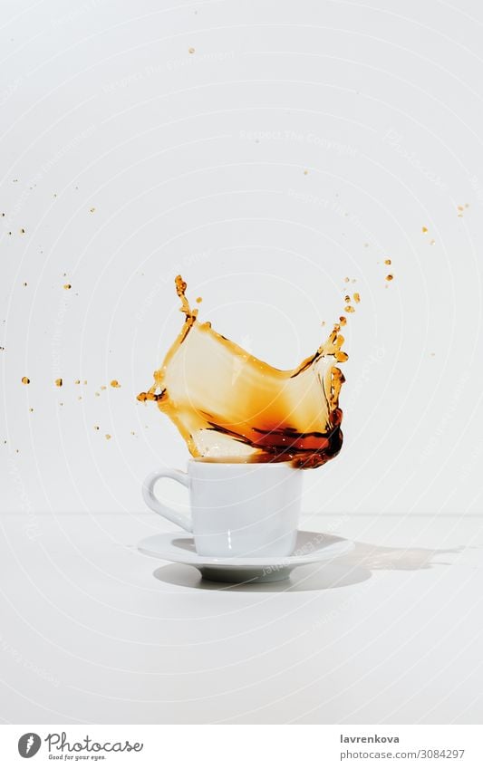 Weiße Tasse und Untertasse mit spritzendem Kaffee minimalistisch Bewegung Espresso Becher Tee aromatisch schwarz platschen Getränk Flüssigkeit liquide heiß weiß