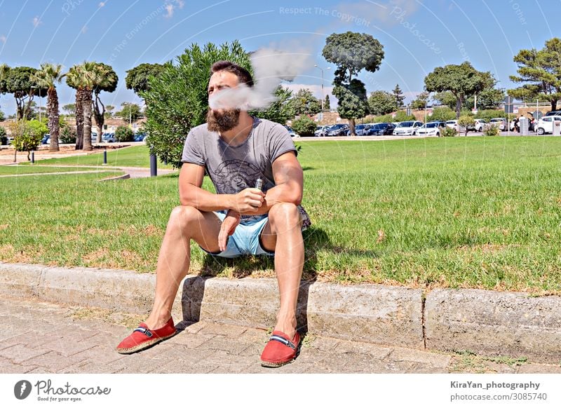 Viper Kaukasischer erwachsener bärtiger Hipster sitzt auf Gras und genießt das Wetter im Park Vollbart Erwachsener Mann Kaukasier männlich Porträt jung Mode