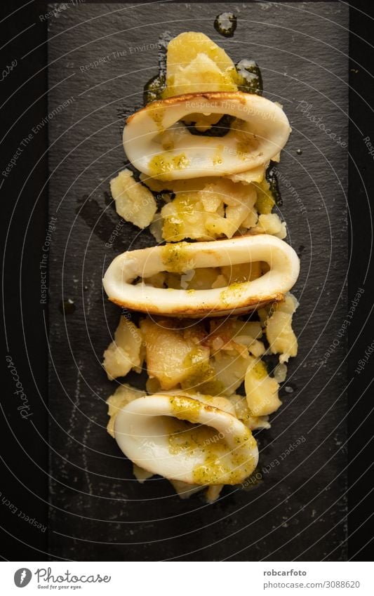 Spanisches Tintenfisch-Top mit Kartoffeln Meeresfrüchte Mittagessen Abendessen Teller Tisch Restaurant Holz frisch lecker rot Tradition Amuse-Gueule Hintergrund