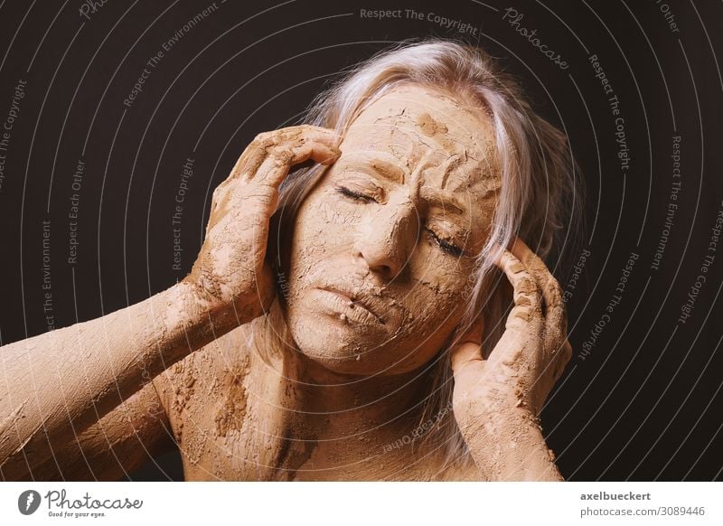 Frau, die mit trockener, gerissener Tonschlammmaske bedeckt ist, die ihren Kopf hält. schön Haut Gesicht Gesundheit Krankheit Wellness Mensch Junge Frau