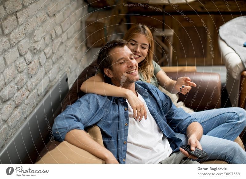Lächelndes junges Paar zum Entspannen und Fernsehen zu Hause Lifestyle Freude schön Erholung Sofa Technik & Technologie Mensch Frau Erwachsene Mann