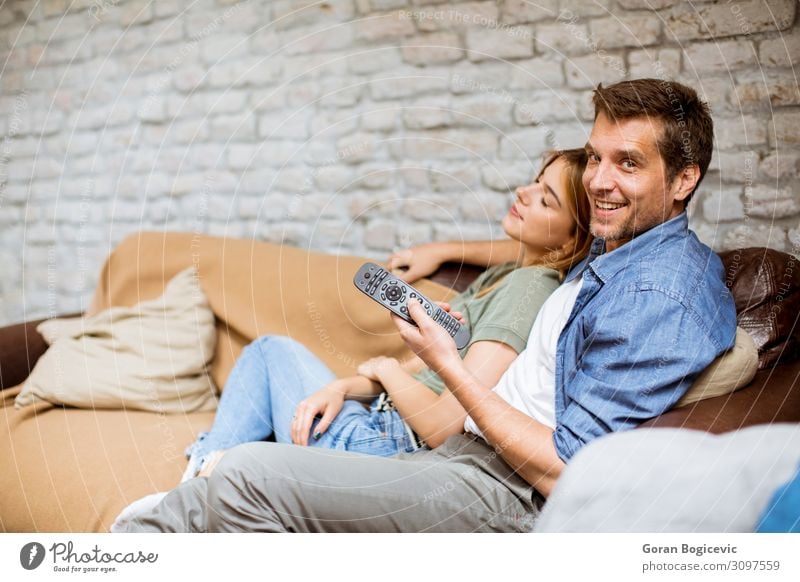 Lächelndes junges Paar zum Entspannen und Fernsehen zu Hause Lifestyle Freude Erholung Wohnung Sofa Technik & Technologie Mensch Frau Erwachsene Mann