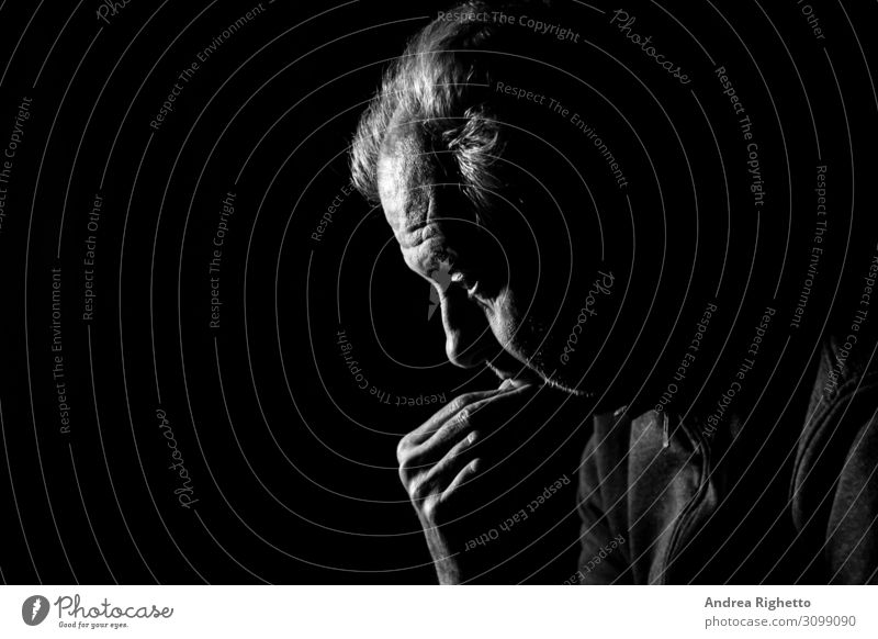 Begriff der Depression. Ein alter Mann, der im Dunkeln in schwarz-weiß mit schwarzem Hintergrund auf nichts starrt. Gesundheitswesen Behandlung Seniorenpflege
