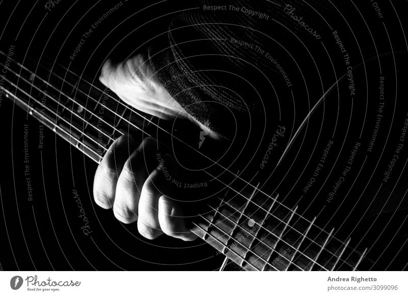 Hand hält eine Akustikgitarre mit schwarzem Hintergrund mit einem dramatischen und filmischen Ton in Helldunkel Mann Erwachsene Kunst Künstler Ausstellung