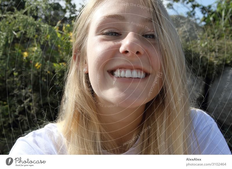 Sehr nahes Portrait einer jungen, blonden Frau, die frech in die Kamera lächelt Lifestyle Freude schön Wellness Leben Sommer Sommerurlaub Sonnenbad Junge Frau