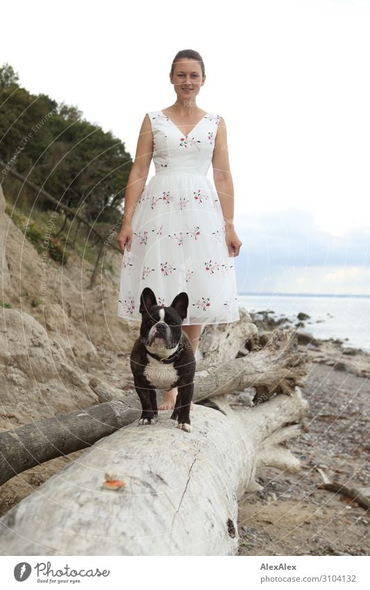 Junge Frau und Französische Bulldogge auf Baumstamm am Strand elegant Stil Freude schön harmonisch Meer Jugendliche 18-30 Jahre Erwachsene Schönes Wetter Ostsee