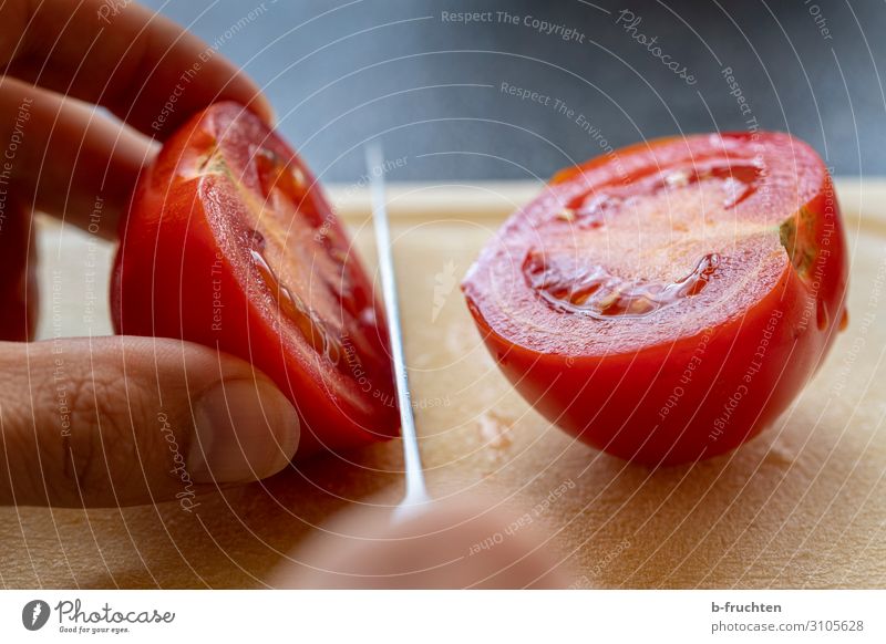 Tomate schneiden Lebensmittel Gemüse Salat Salatbeilage Ernährung Bioprodukte Vegetarische Ernährung Messer Tisch Küche Arbeitsplatz Finger festhalten frisch