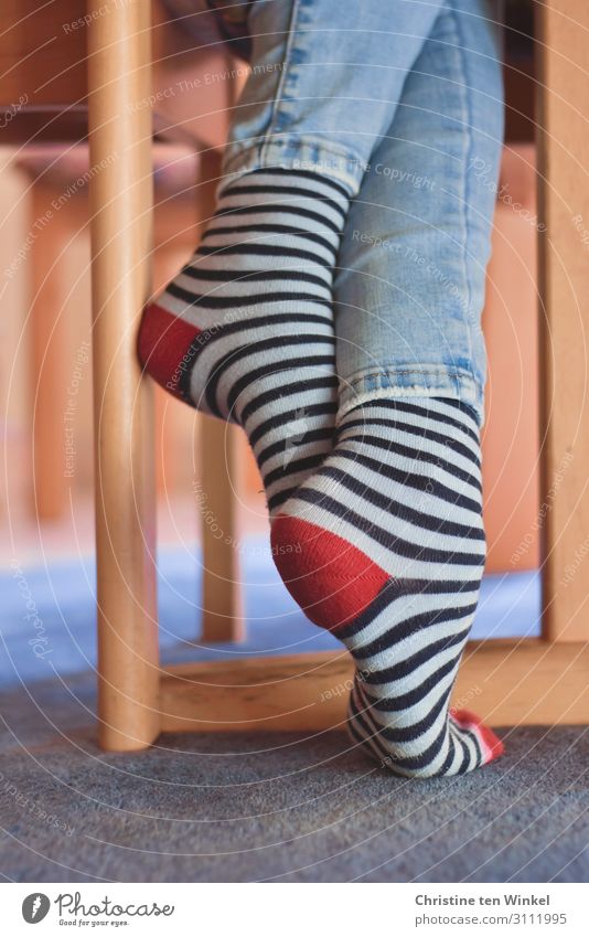Wärmende Ringelsocken und Jeans an schlanken verschränkten Beinen Socken Jugendliche Jeanshose authentisch Fröhlichkeit kuschlig trendy feminin Coolness Wohnung