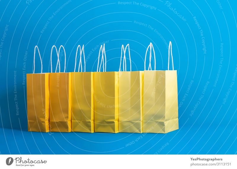 Gelbe Einkaufstaschen auf blauem Hintergrund, Einkaufskonzept Lifestyle kaufen Freude Glück Winter Feste & Feiern Weihnachten & Advent Silvester u. Neujahr