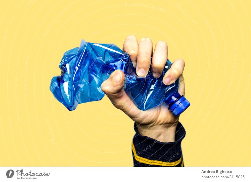 Konzept zur Beendigung der Kunststoffverschmutzung, der globalen Erwärmung, des Recyclings von Kunststoffen, frei von Kunststoffen. Eine leere blaue Plastikflasche wird als Zeichen des Protests mit der Hand fest zusammengedrückt. Gelber Hintergrund mit einem isolierten Thema