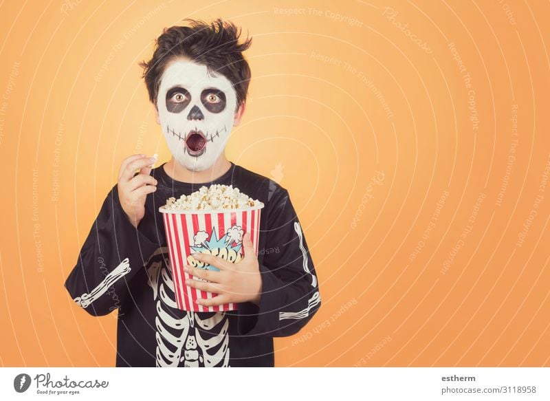 Happy Halloween.überrascht Kind in einem Skelett-Kostüm mit Popcorn gegen orange Hintergrund Lebensmittel Essen Behandlung Entertainment Feste & Feiern Mensch